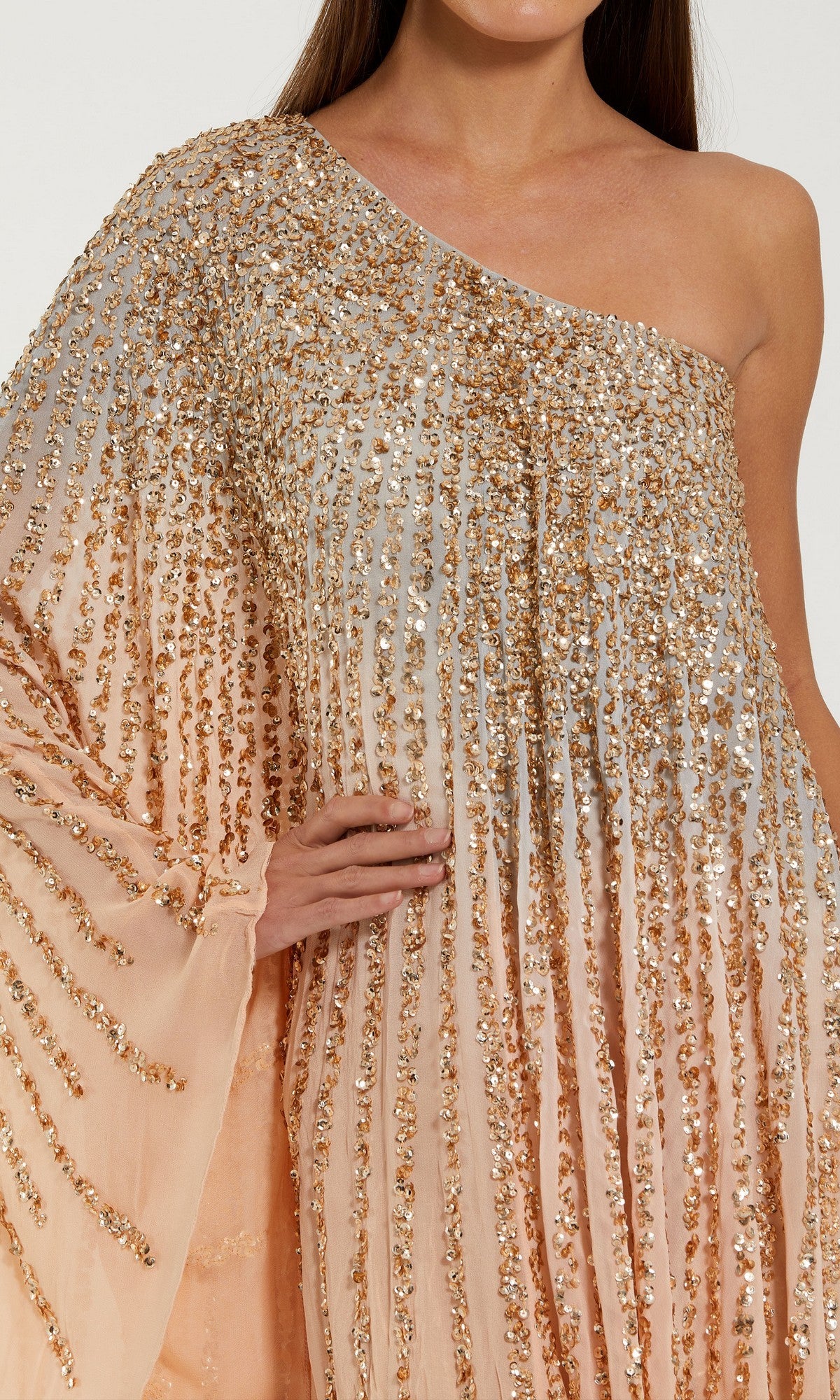 A person wearing the Tea-Length Party Dress: Mac Duggal 6204—a peach ombre mesh sequin dress featuring a one-shoulder neckline and gold sequin embellishments—stands with one arm bent and hand on hip.